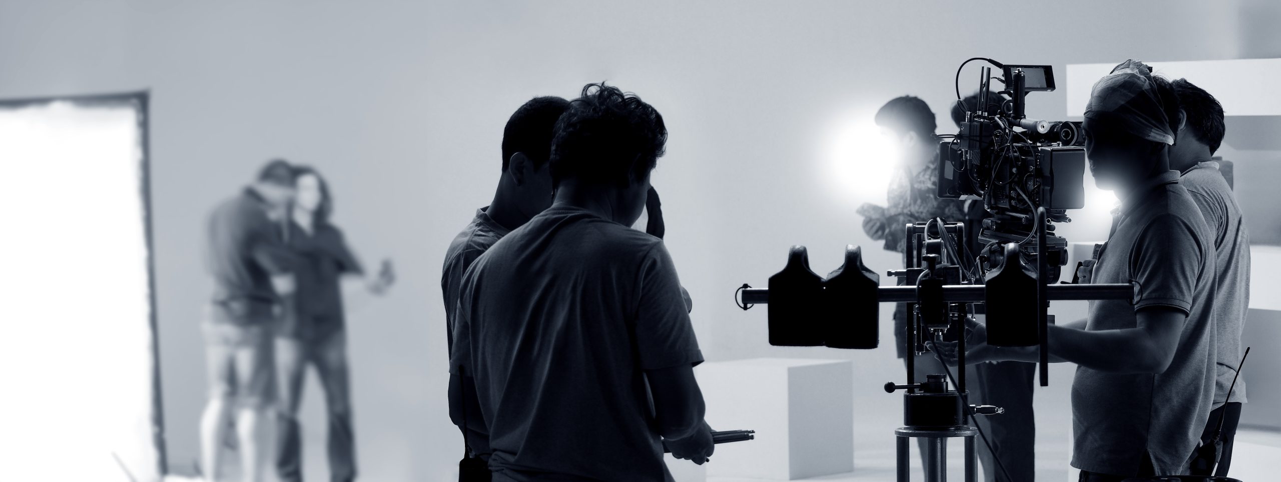 Lots of people standing near a camera setting it up for filming